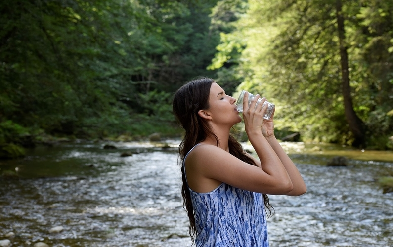 girl drinking a glass of water near a stream | health and weight loss | Peace Evolution