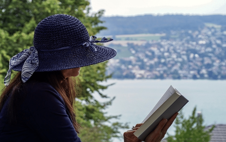 girl sitting next to a lake reading | practice water fasting | Peace Evolution