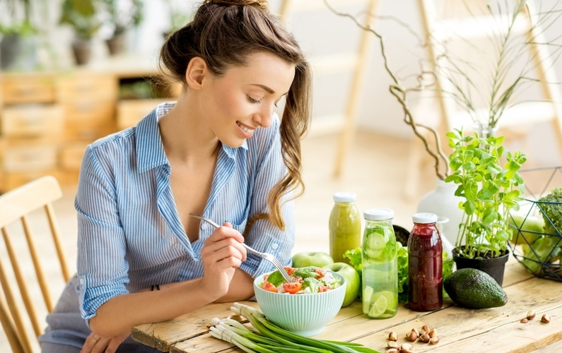 woman sitting at table eating a salad | eating vegan | Peace Evolution